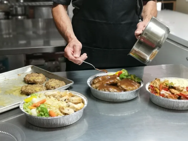 Un traiteur prépare des repas qu'il met ensuite dans des portions individuelles pour les vendre dans un distributeur de plats cuisinés.