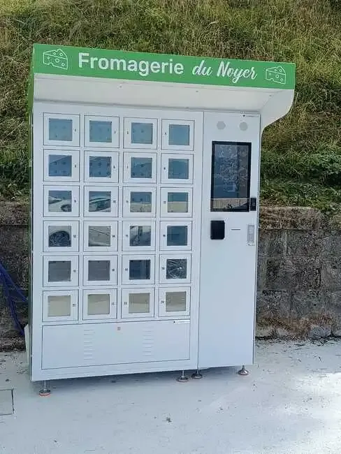 Photo du distributeur multiproduits de la Fromagerie du Noyer, avec son abri minimaliste et sa borne de commande tactile.