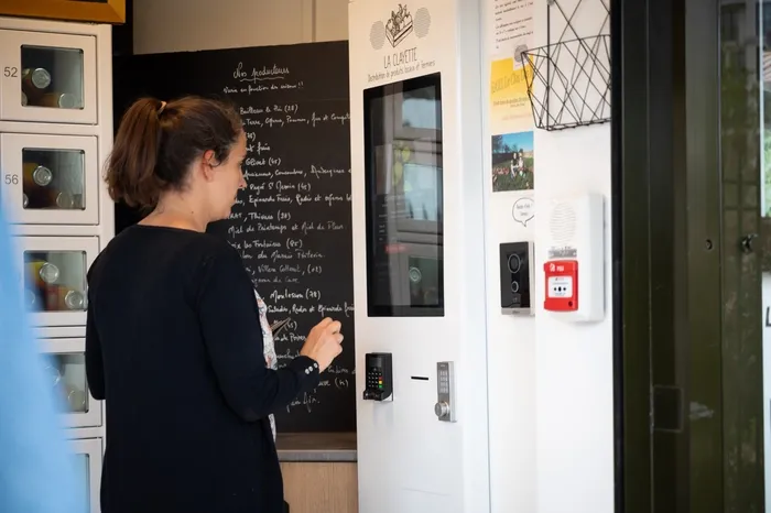 Une cliente achète le contenu d'un casier du distributeur de plats cuisinés à l'aide de la borne de commande connectée.